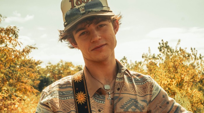 A man wearing a western printed shirt, cap, and sunglasses